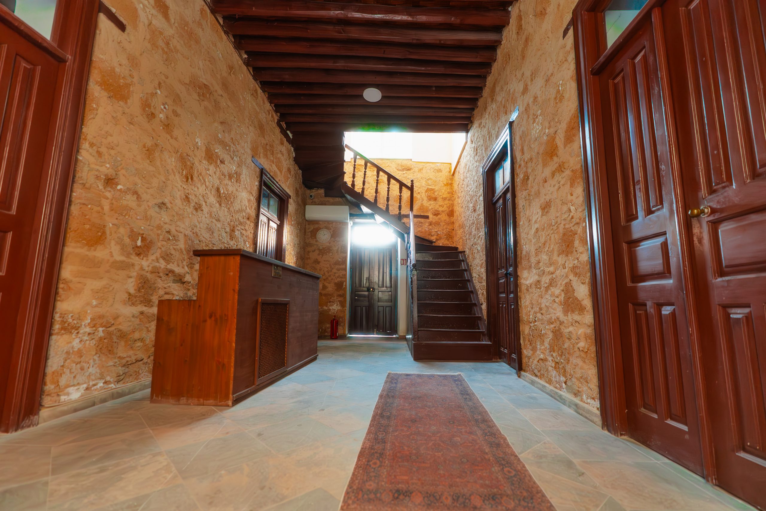 Stone-walled entrance hallway of Zuma Hotel with a traditional Cypriot rug